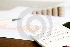 A Selective focus calculator, pencil , coin on chart document.