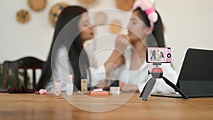 Selective focus camera and women are showing how to make up via online video at the dressing table