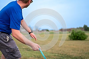 Selective focus on a Caucasian adult preparing to sidearm throw a disc golf towards the pin. photo