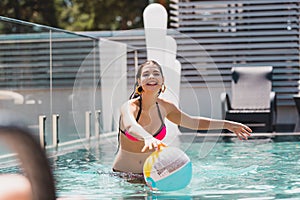 Focus of cheerful girl in swimwear reaching beach ball in swimming pool