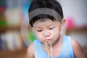 Selective focus. Child uses the mouth to take the strands of food and inhale. On a cloudy day Children eat instant noodles.