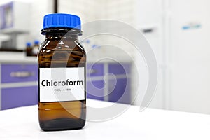 Selective focus of chloroform or trichloromethane liquid chemical in glass amber bottle inside a chemistry laboratory.
