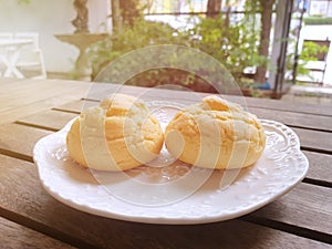 Selective focus of Choux cream in white plate on wooden table with sun shining in cafÃƒÂ©