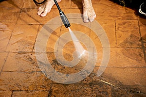 Selective focus. Cleaning backyard paving tiles with high pressure washer