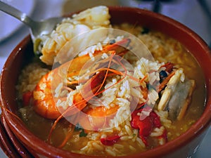 Selective focus, Close up authentic traditional Portuguese seafood soup with rice, arroz de marisco red bowl