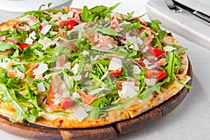 Selective focus Close up Delicious Pizza with hamon and cherry tomato slices, parmezan cheese and arugula on the wooden board