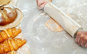 Selective focus and close up on hands using rolling pin to teach and thresh dough flour to make pie and bread for serving on table