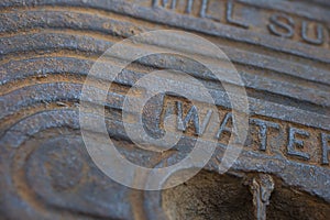 A detail of an old steel water meter cover dug out of the ground photo