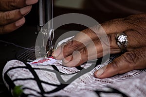 Selective focus close up of tailor`s hand using a sewing machine