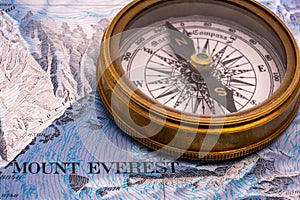 Selective focus close up of vintage brass compass on map detail of Mt. Everest topographical map showing contour lines photo