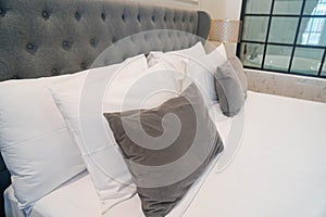 Selective focus close up white and grey pillows on double bed in luxury 5 stars hotel