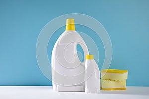 Selective focus closeup of gallons of cleaning detergent and sponges on a blue background