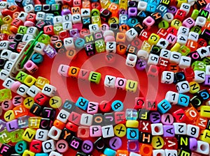 Selective focus.Colorful dice with word LOVE YOU on a red background.Shot were noise and film grain.