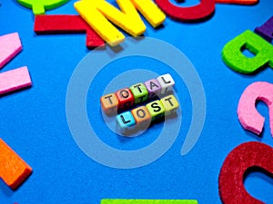 Selective focus.Colorful dice with word TOTAL LOST on blue background.Shot were noise and film grain.