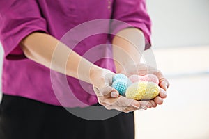Selective focus colorful multicolor knitting hearts held by female`s both hands, representing helping hands, supports, assistance