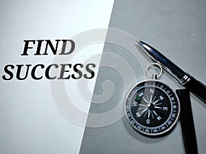 Selective focus.Compass and pen with word FIND SUCCESS on a white and gray background.Business concept.