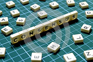 Selective focus of Consensus word made of square letter block on green square mat background