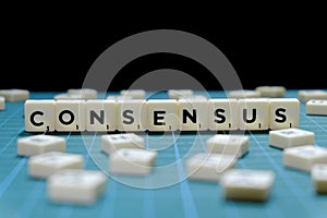 Selective focus of Consensus word made of square letter block on green square mat background