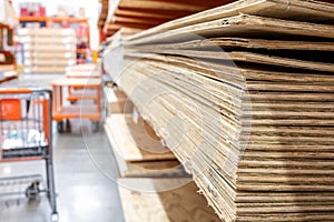 Selective focus on corner edge of stacked plywood at a lumberyard hardware store.