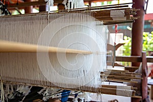 Selective focus of cotton thread on weaver machine. Thai cotton handmade. Homespun fabric process. The process of fabric weaving