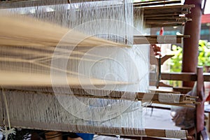 Selective focus of cotton thread on weaver machine. Thai cotton handmade. Homespun fabric process. The process of fabric weaving