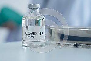 Selective focus on Covid-19 vaccine bottle on table. And next to it is syringe and tray at laboratory hostipal