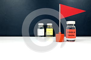 Selective focus of covid-19 vaccine vial beside a red flag. Coronavirus vaccine candidate development race and competition winner