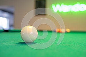 Selective focus of a cue ball on a billiard table under the lights in a club