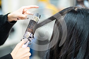 Selective focus at curl equipment of Hair stylish while do hairdressing and put care treatment while styling curly hair for client