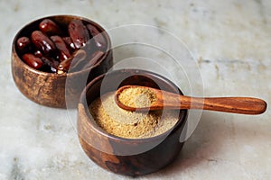 selective focus of dates with dates sugar on wooden bowls.