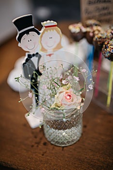 Selective focus of a decorated table with flowers in a vase, groom and bride miniature for a wedding