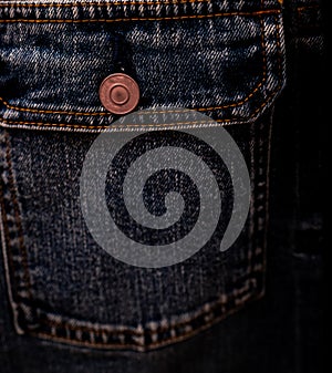 Selective focus on denim jean jacket pocket in clothes shop. Denim jacket pocket and button texture. Textile industry. Jeans