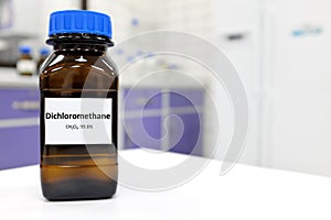 Selective focus of dichloromethane liquid chemical compound in dark glass bottle inside a chemistry laboratory with copy space.