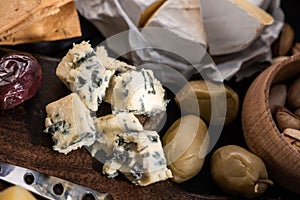 Selective focus of dorblu with dried olives, bowl of pistachios, camembert and crackers on tray.