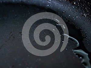 Selective focus on drops of hot oil on the surface of the pan. Abstract food background