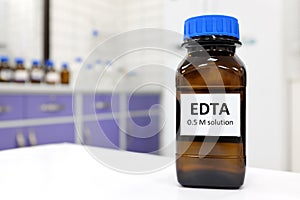 Selective focus of EDTA liquid chemical compound reagent solution in dark glass bottle inside a chemistry laboratory.