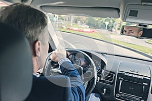 Selective focus of elderly man hands on steering wheel driving a car on the speed highway. View from above.