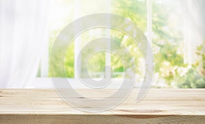 selective focus.Empty of wood table top on blur of curtain window and abstract green from garden with sunlight .For montage