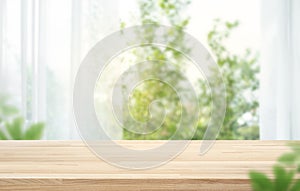 Selective focus.Empty of wood table top on blur of curtain with window and green from garden background