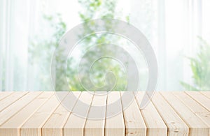 Selective focus.Empty of wood table top on blur of curtain with window and green from garden background