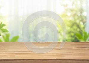 Selective focus.Empty of wood table top on blur of curtain with window view green from garden