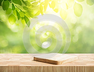 Selective focus.End grain wood counter top with cutting board on blur greeny tree garden in morning background.For montage product photo