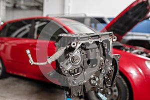 Selective focus. Engine Block on a repair stand with Piston and Connecting Rod of Automotive technology. Blurred red car