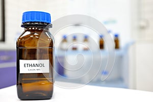 Selective focus of ethanol or ethyl alcohol brown amber glass bottle inside a laboratory. Blurred background with copy space.