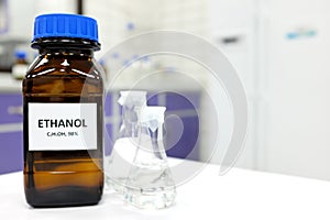 Selective focus of ethanol or ethyl alcohol in brown glass bottle inside a laboratory.