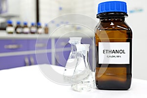 Selective focus of ethanol or ethyl alcohol in brown glass bottle inside a laboratory.