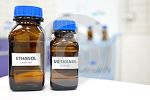 Selective focus of ethanol and methanol brown amber glass bottle inside a laboratory. Blurred background with copy space.