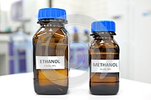 Selective focus of ethanol and methanol brown amber glass bottle inside a laboratory. Blurred background with copy space.