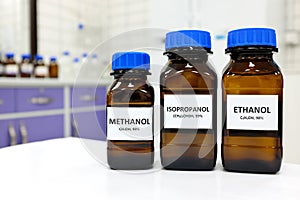 Selective focus of ethanol, methanol and isopropanol brown amber glass bottles inside a laboratory. Different types of alcohol.