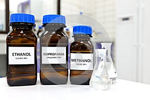 Selective focus of ethanol, methanol and isopropanol brown amber glass bottles inside a laboratory. Different types of alcohol.